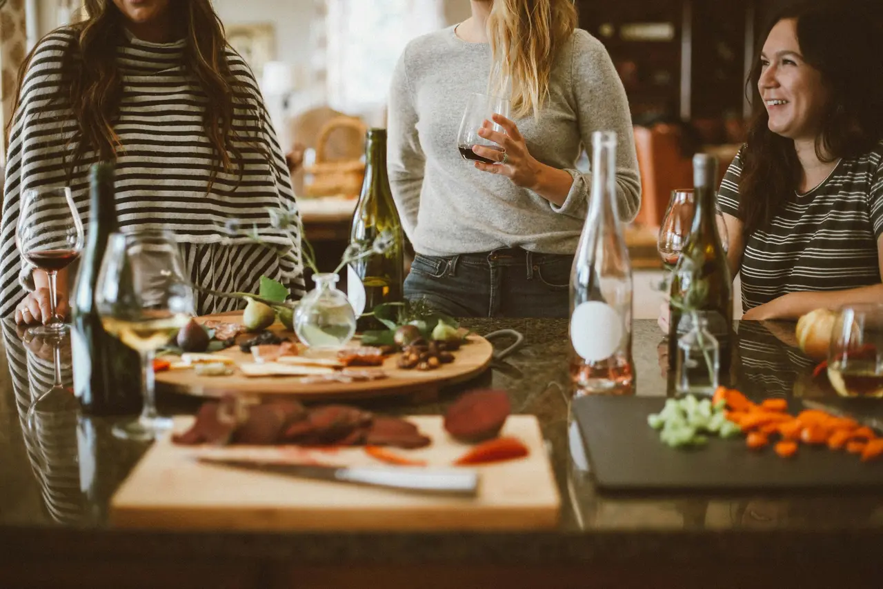 Tisch mit verschiedenen Speisen und im Hintergrund drei Frauen